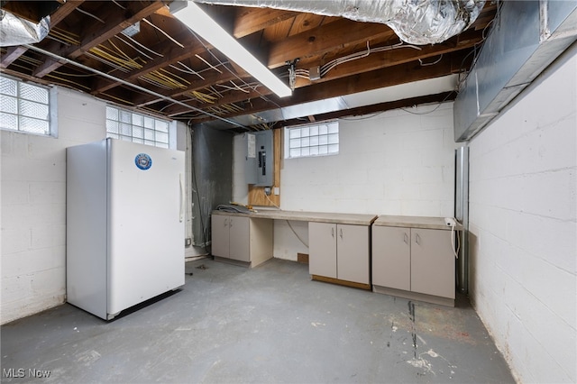 basement with electric panel and freestanding refrigerator