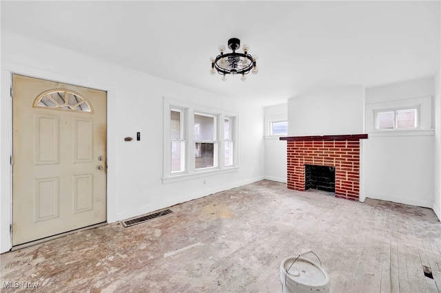 unfurnished living room with a brick fireplace, visible vents, and baseboards