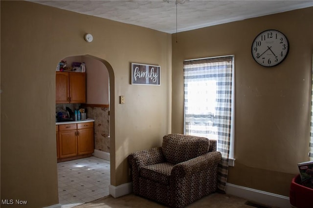 sitting room with light floors, visible vents, baseboards, and arched walkways