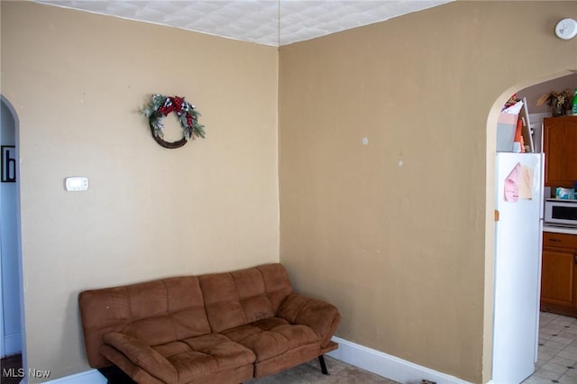 sitting room featuring arched walkways and baseboards