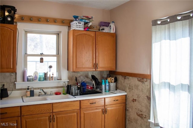 kitchen featuring brown cabinets, light countertops, and a sink