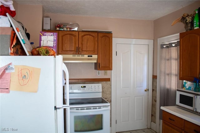 kitchen featuring a textured ceiling, under cabinet range hood, white appliances, light countertops, and brown cabinets