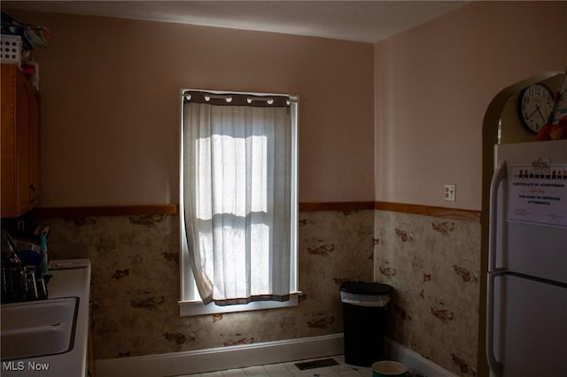 kitchen with freestanding refrigerator, a wainscoted wall, a sink, and visible vents