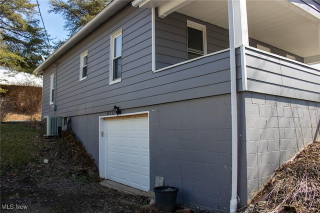 view of side of home featuring an attached garage and central AC unit