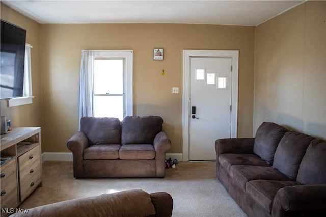 living area featuring light carpet and baseboards