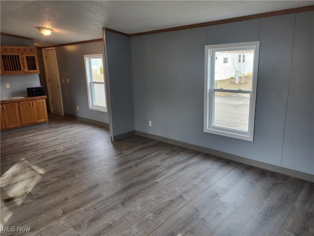 7443 Spillway Rd Lot 25, Lisbon, OH 44432 - unfurnished living room featuring a textured ceiling, visible vents, crown molding, and wood finished floors