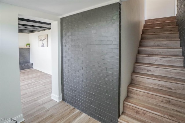 stairs with brick wall and wood finished floors