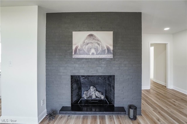 details featuring a brick fireplace, baseboards, wood finished floors, and recessed lighting