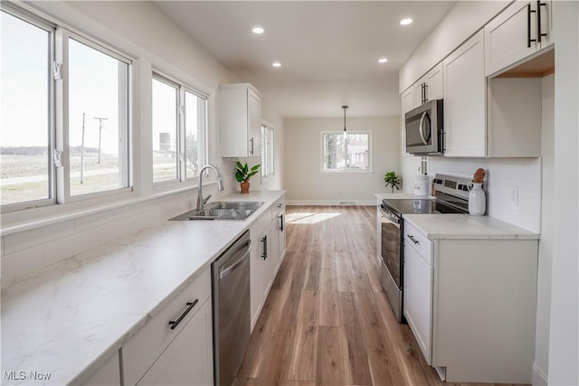 kitchen with recessed lighting, appliances with stainless steel finishes, light wood-style floors, white cabinetry, and a sink