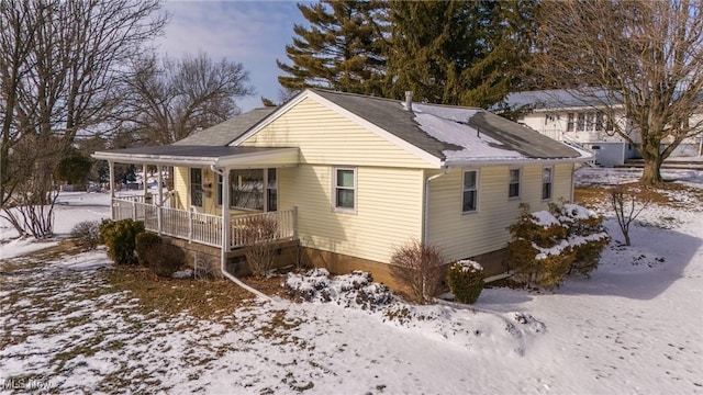 view of snow covered exterior with roof with shingles