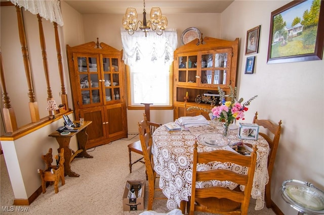 dining space with a chandelier, carpet floors, and baseboards