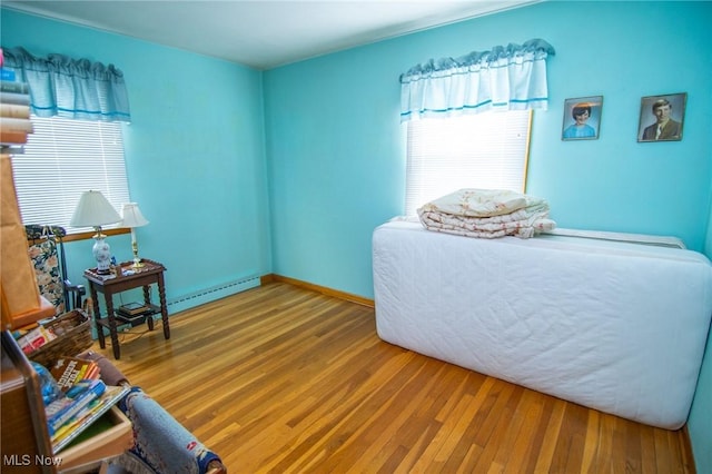 bedroom with a baseboard heating unit and wood finished floors