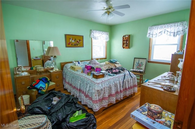 bedroom featuring ceiling fan, multiple windows, and wood finished floors