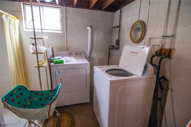 laundry room featuring concrete block wall, laundry area, and independent washer and dryer