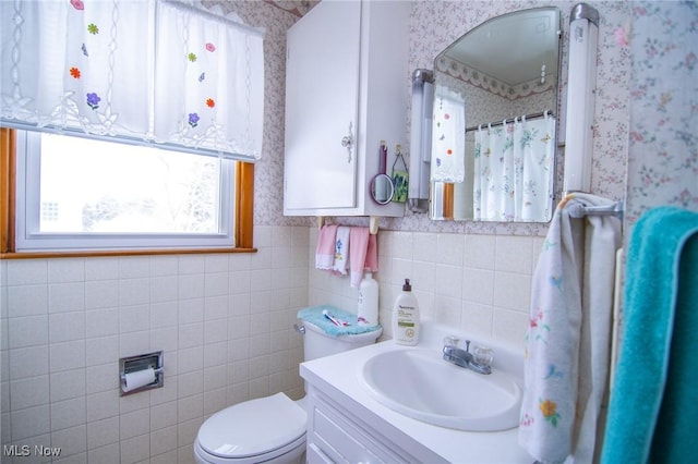 bathroom featuring tile walls, curtained shower, toilet, vanity, and wallpapered walls