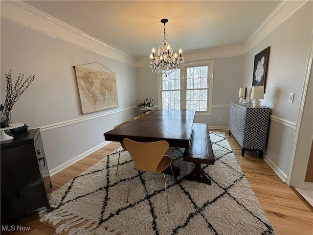 dining room with light wood-type flooring, baseboards, ornamental molding, and a chandelier