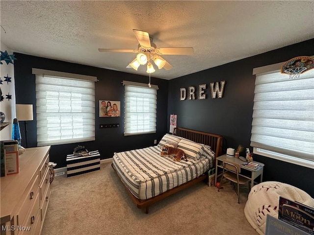 bedroom featuring light colored carpet, ceiling fan, a textured ceiling, and baseboards