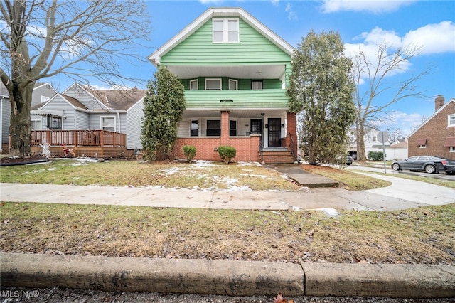 shotgun-style home with a front lawn and brick siding