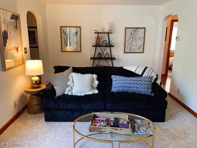 living room with arched walkways, carpet floors, and baseboards