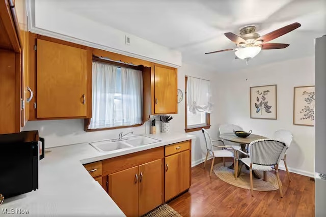 kitchen with light countertops, brown cabinetry, and a sink