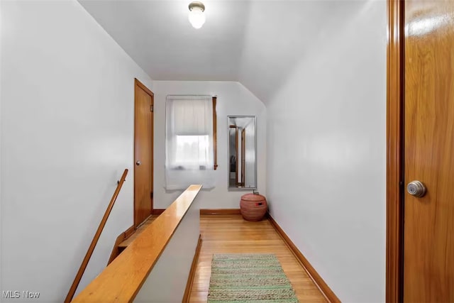 corridor featuring light wood finished floors, baseboards, and an upstairs landing