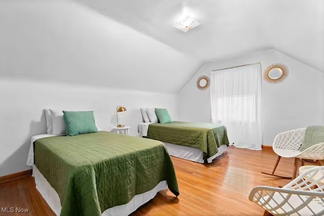 bedroom with baseboards, vaulted ceiling, and wood finished floors