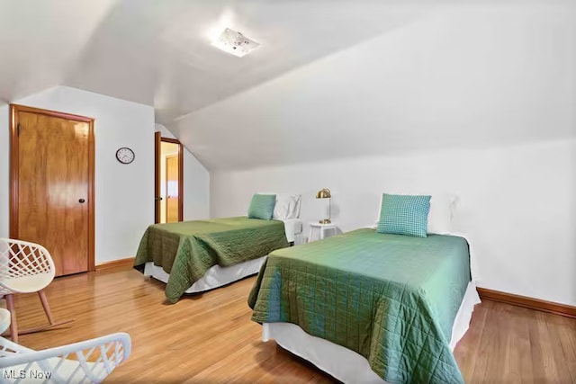 bedroom with lofted ceiling, baseboards, and wood finished floors