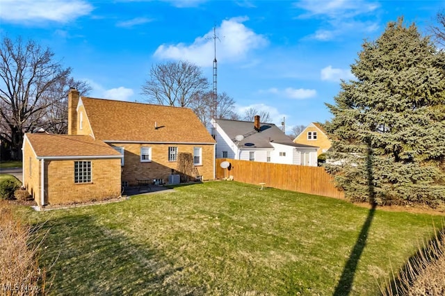 back of house featuring brick siding, a yard, a chimney, a patio area, and fence