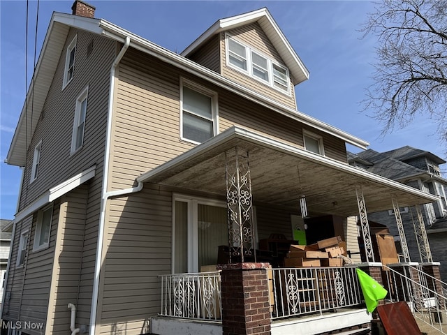 american foursquare style home featuring a porch and a chimney