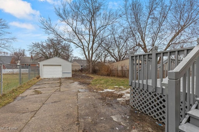 view of yard featuring a garage, an outdoor structure, fence, concrete driveway, and a wooden deck