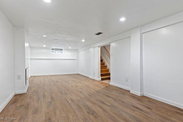 basement with stairway, visible vents, wood finished floors, and recessed lighting