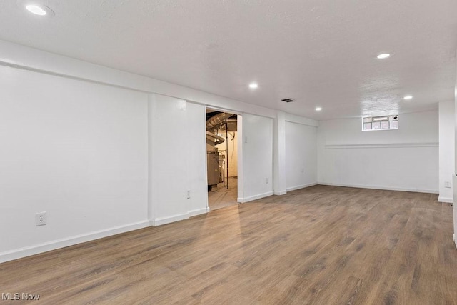 below grade area with baseboards, wood finished floors, visible vents, and recessed lighting