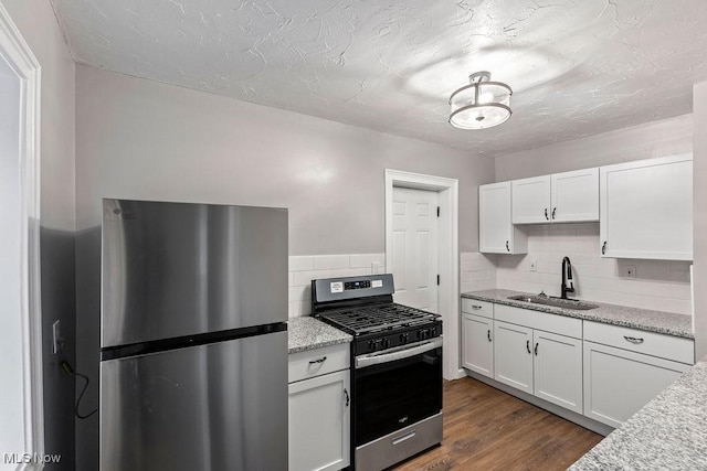 kitchen with appliances with stainless steel finishes, dark wood-type flooring, a sink, and white cabinets