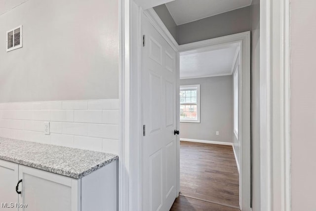 corridor with baseboards, visible vents, and dark wood-style flooring