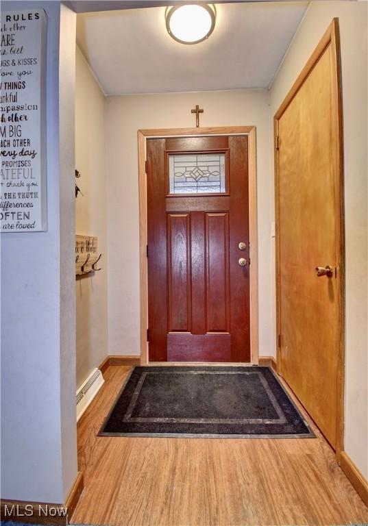 entryway featuring a baseboard heating unit, baseboards, and wood finished floors