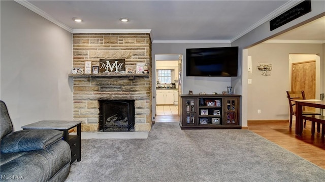 carpeted living area with crown molding, a fireplace, baseboards, and wood finished floors