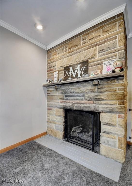 interior details with baseboards, ornamental molding, carpet flooring, and a stone fireplace