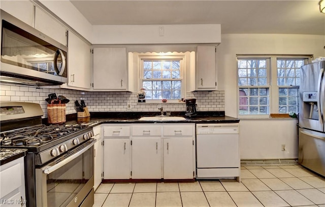 kitchen featuring stainless steel appliances, dark countertops, a sink, and tasteful backsplash