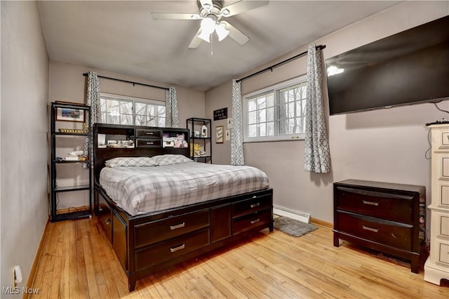 bedroom with light wood-style flooring, multiple windows, a baseboard heating unit, and baseboards