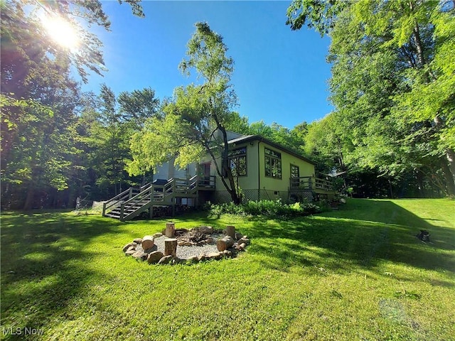 view of yard featuring a deck, stairway, and a fire pit