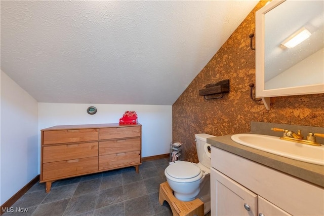 bathroom with a textured ceiling, vaulted ceiling, vanity, and baseboards