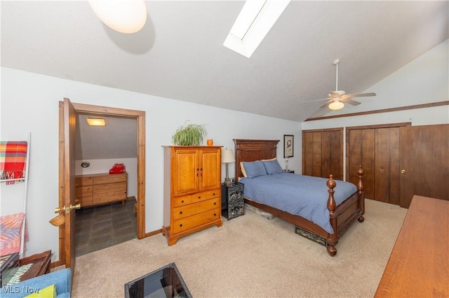 bedroom featuring light carpet, lofted ceiling with skylight, and a ceiling fan