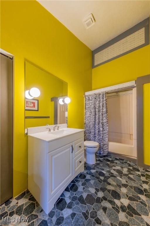 bathroom with visible vents, stone finish flooring, vanity, and toilet