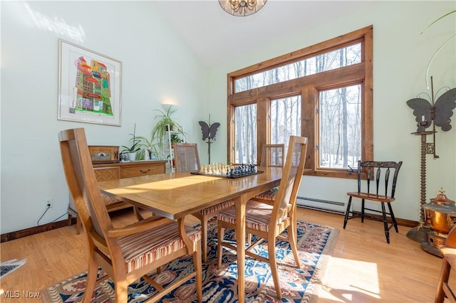 dining area featuring light wood-style floors, vaulted ceiling, and baseboards