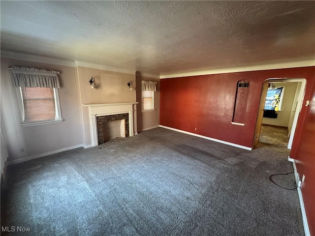 unfurnished living room featuring baseboards, arched walkways, a textured ceiling, carpet flooring, and a fireplace