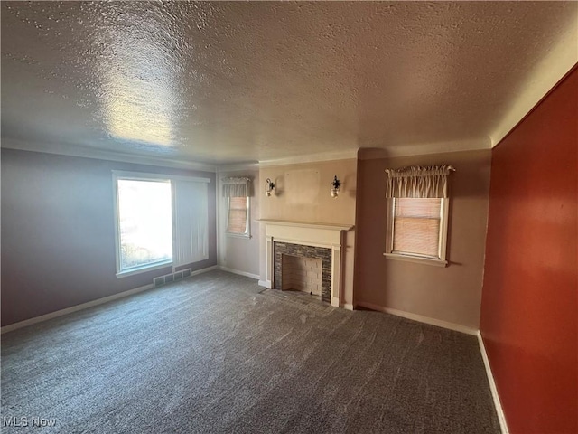 unfurnished living room with a textured ceiling, a fireplace with flush hearth, visible vents, baseboards, and carpet