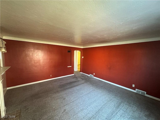 spare room featuring arched walkways, dark carpet, visible vents, and baseboards