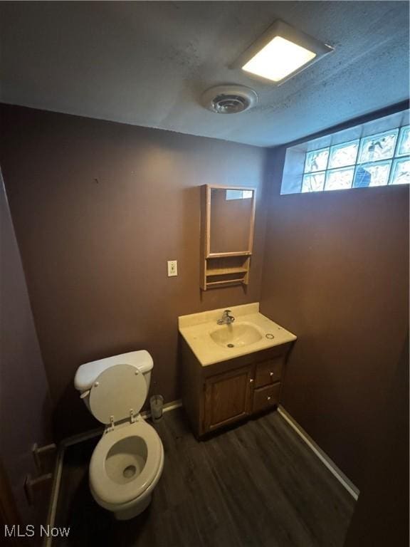 bathroom featuring baseboards, vanity, toilet, and wood finished floors