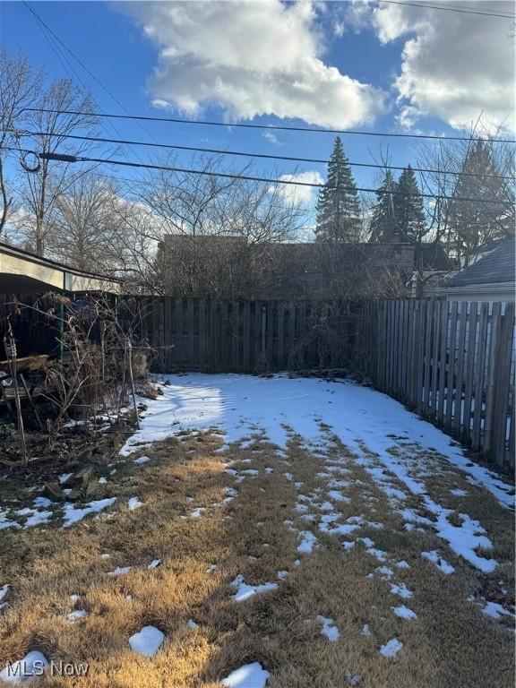 snowy yard featuring a fenced backyard