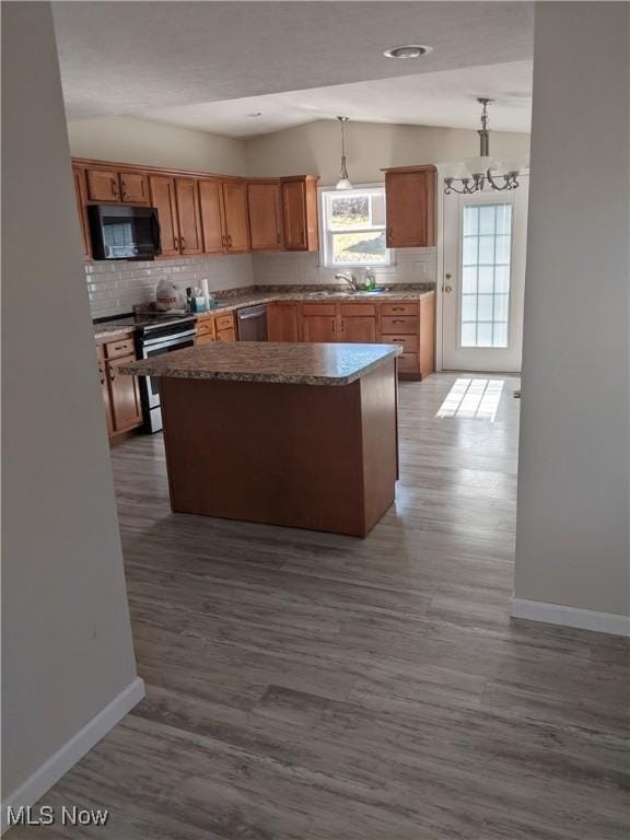 kitchen with stainless steel appliances, vaulted ceiling, a center island, tasteful backsplash, and dark wood finished floors